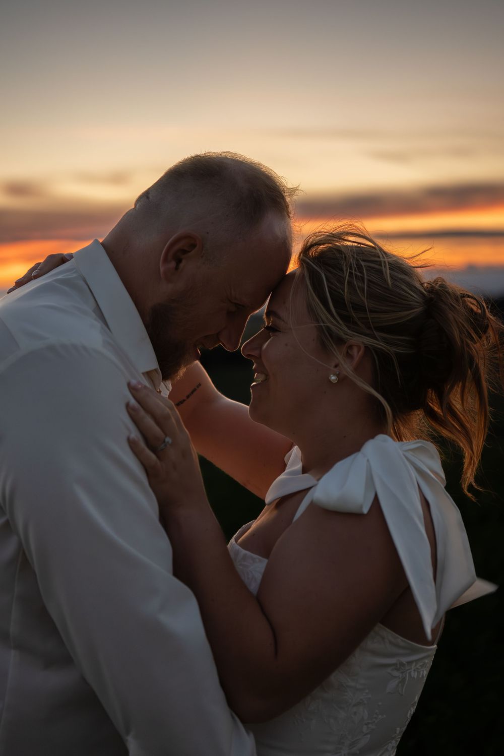 A romantic silhouette of a couple embracing against a dramatic sunset sky.