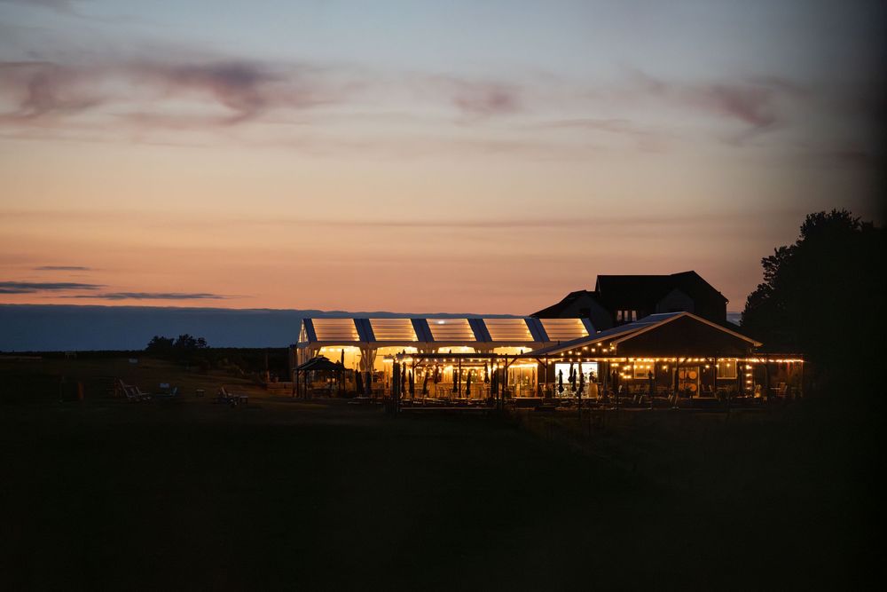 Silhouette of a ranch house with warm glowing windows against a dramatic sunset sky.