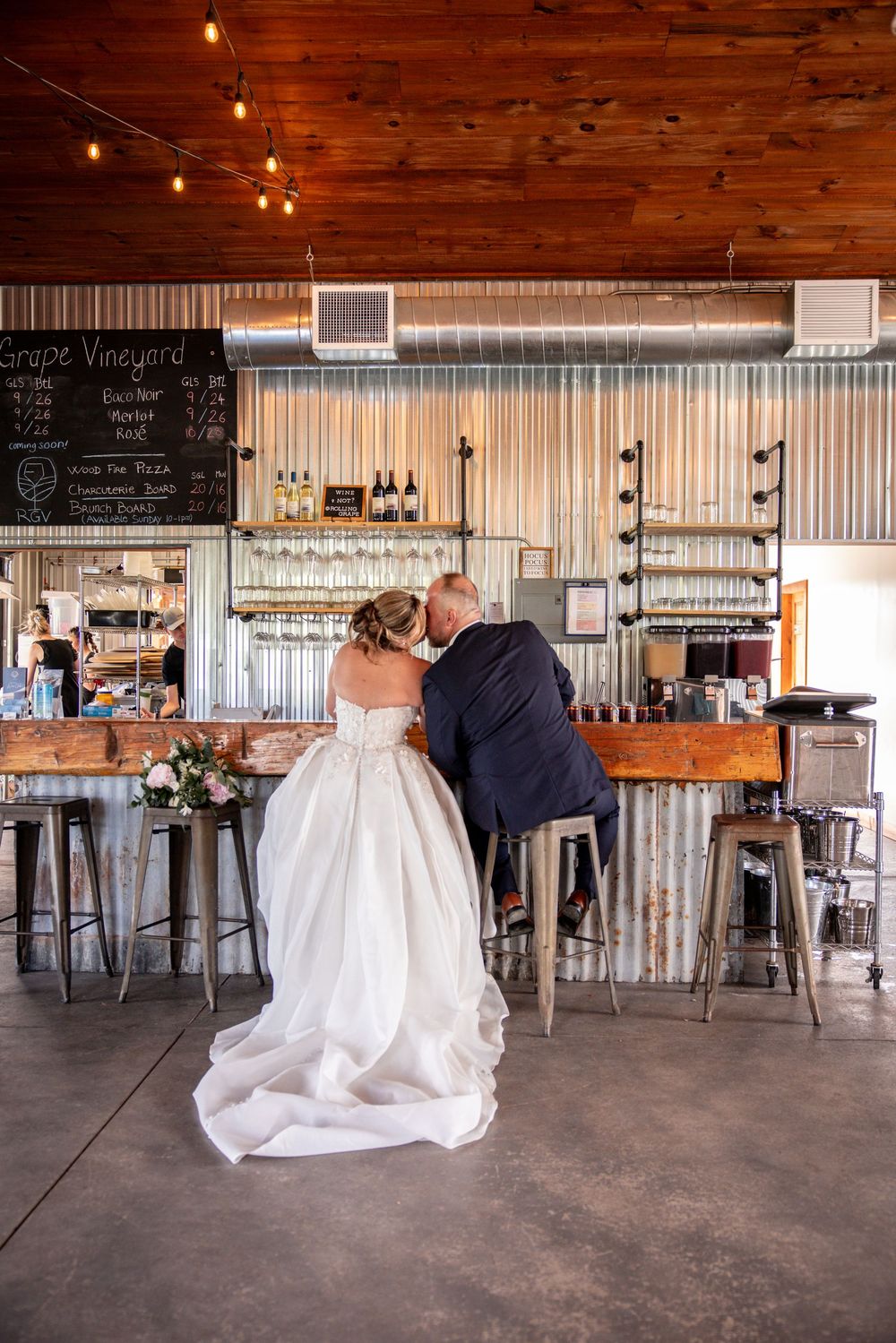 A wedding couple shares a quiet moment in a rustic venue with wooden ceilings and industrial decor.