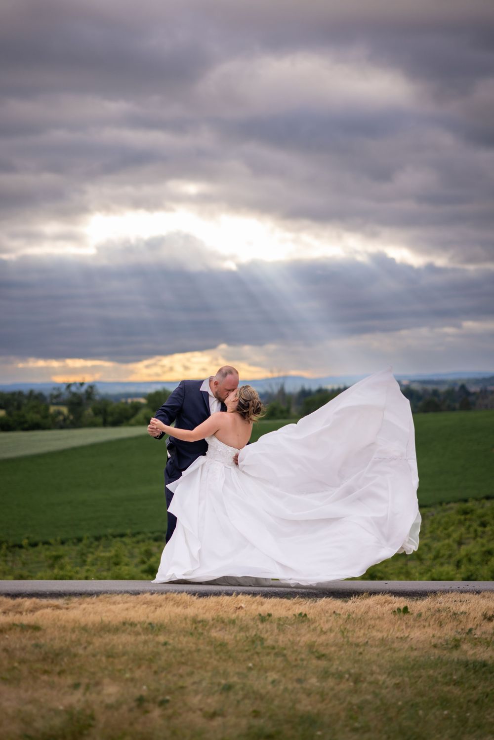 A dramatic wedding photo sequence shows a white veil flowing in the wind against a moody cloudy sky over green fields.