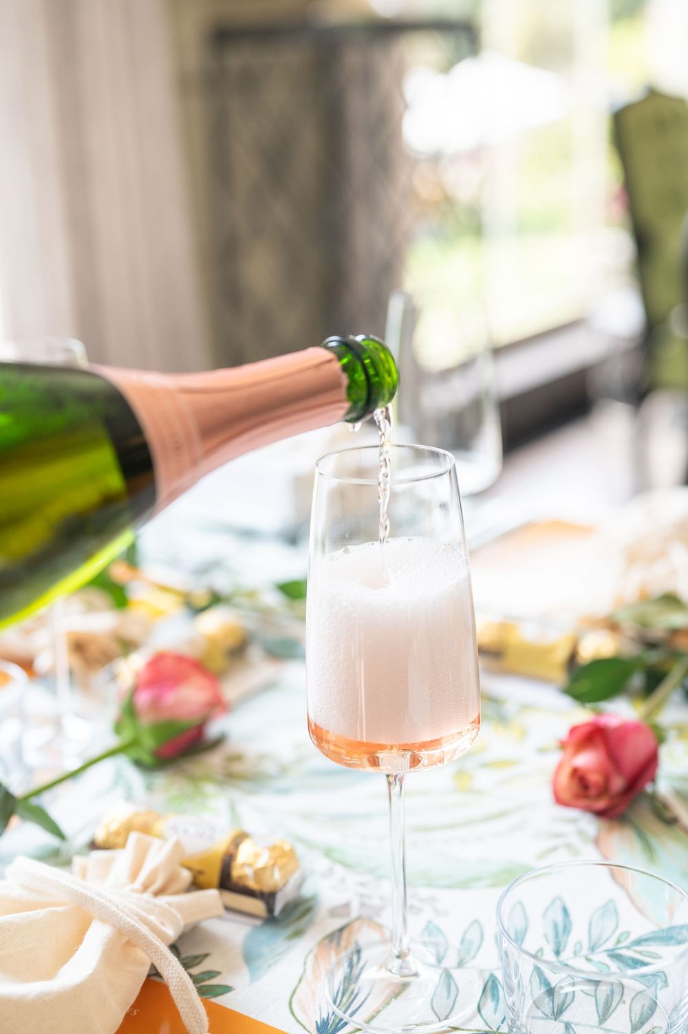 Elegant table setting with pink roses, champagne glasses, and soft natural lighting creating a romantic atmosphere.
