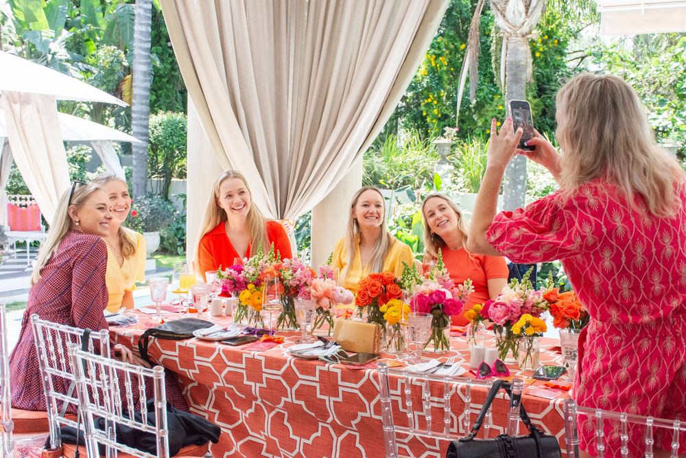Elegant outdoor party setup with white drapes, dining tables, and colorful floral centerpieces.