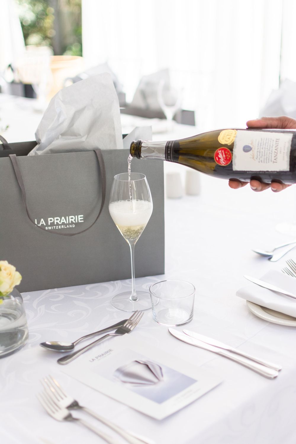 Wine glasses and place settings arranged on a white tablecloth at an elegant dining establishment.