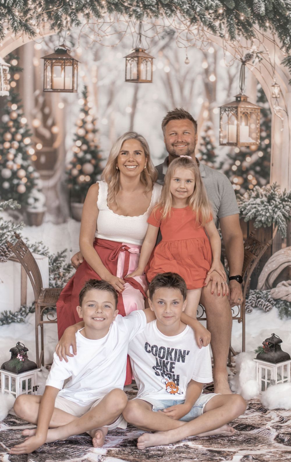 Family poses together in a dreamy winter wonderland setting with lanterns and twinkling lights in the background.