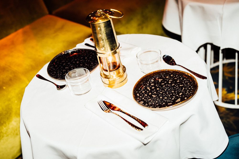 A table setting with champagne bottle, glasses, and a plate of black caviar on crisp white linen.