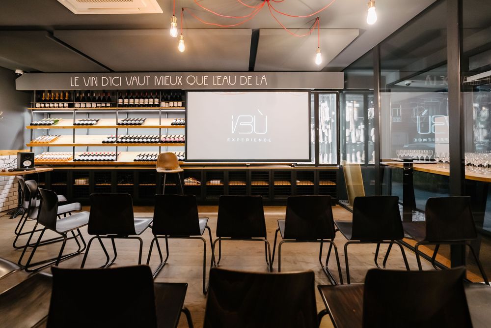 Modern classroom setup with black chairs facing a projector screen and shelves of products displayed along the wall.