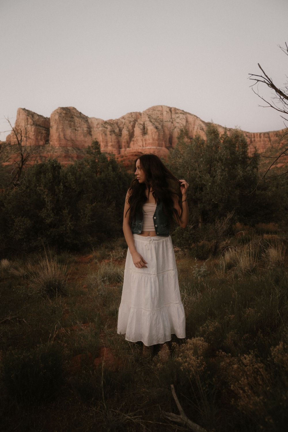 Dreamy desert photoshoot with red rock formations and white maxi skirt at sunset.