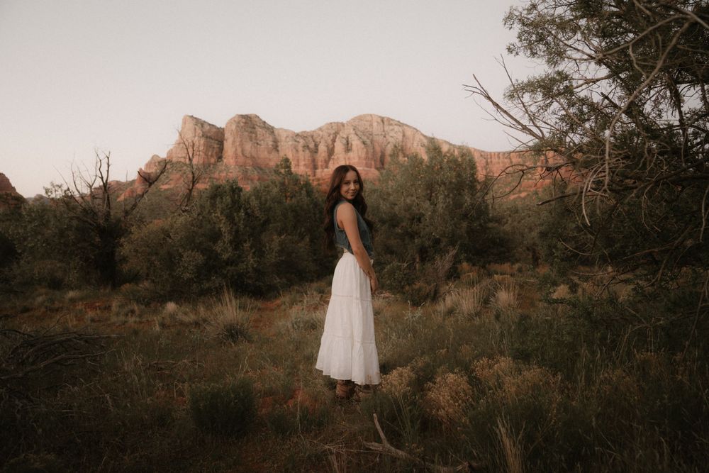 Silhouetted figure in white dress against majestic red rock formations in Arizona.