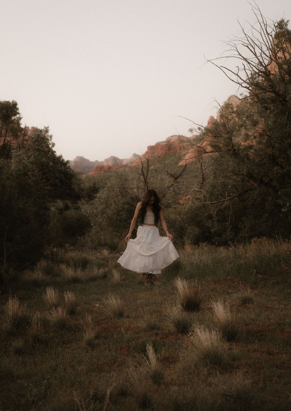 Ethereal portrait with flowing white dress against desert brush and distant mountains.