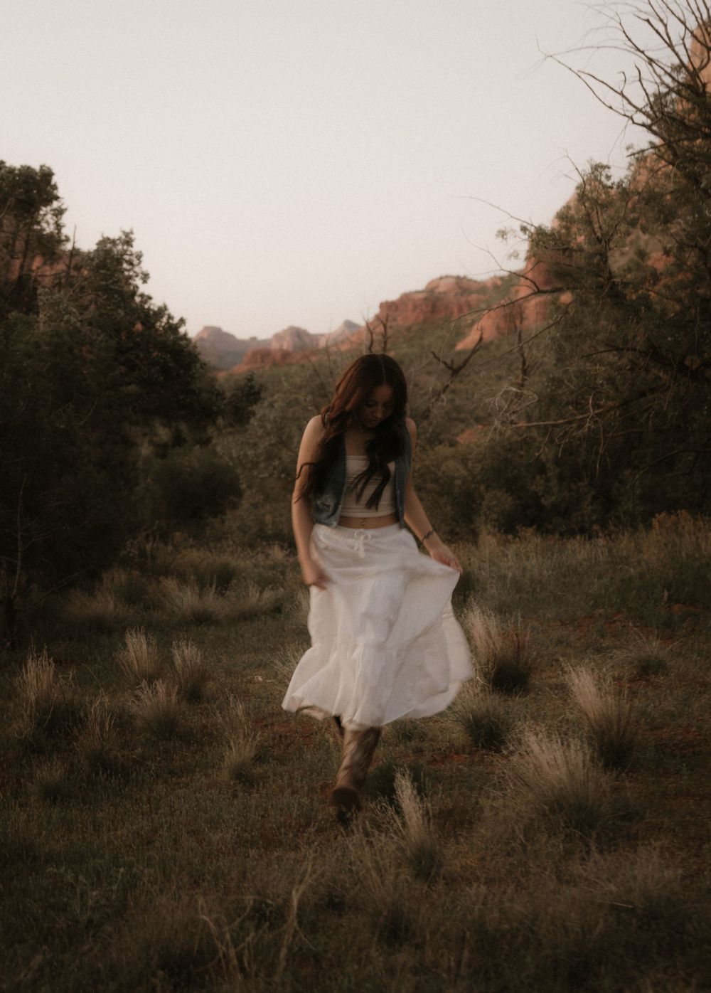 Artistic movement captured in white dress against desert landscape at sunset.
