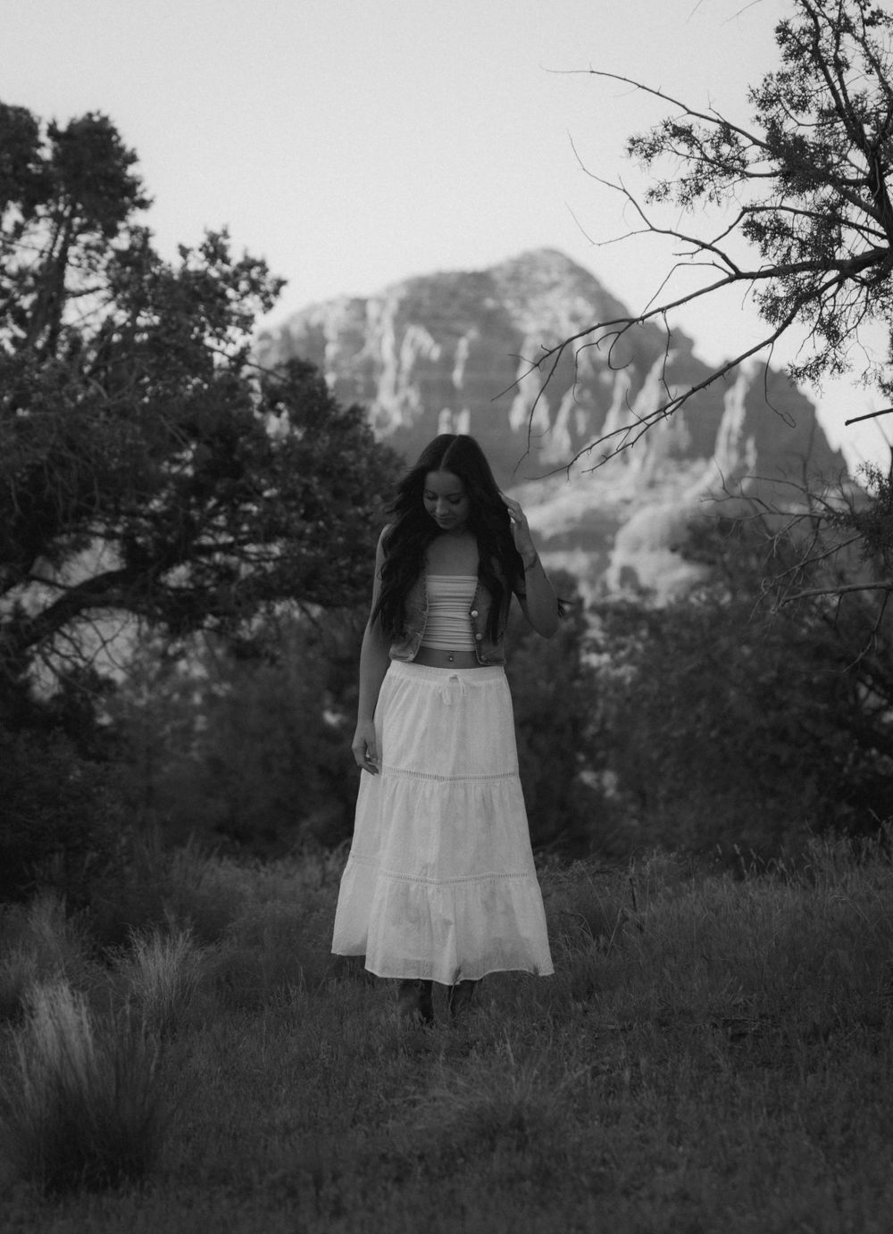 A long white skirt stands out against the rocky mountain landscape in monochrome.