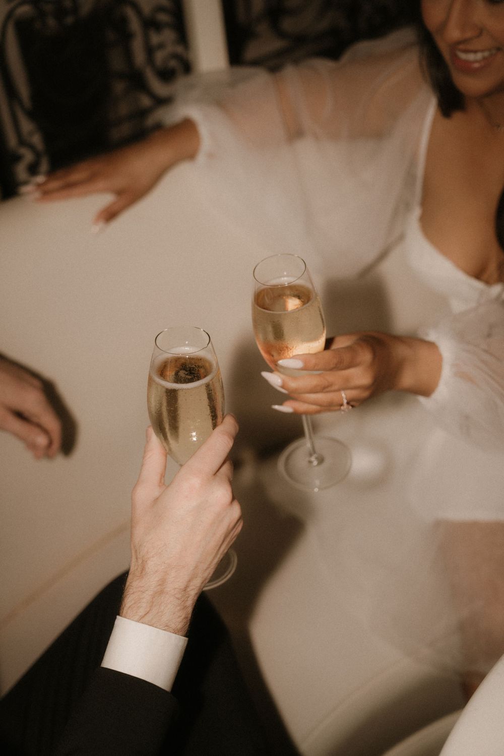 Hands clink champagne glasses in an intimate wedding celebration.