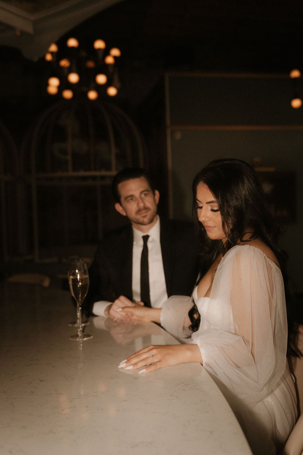 A couple enjoys champagne at an elegant venue with ambient lighting.