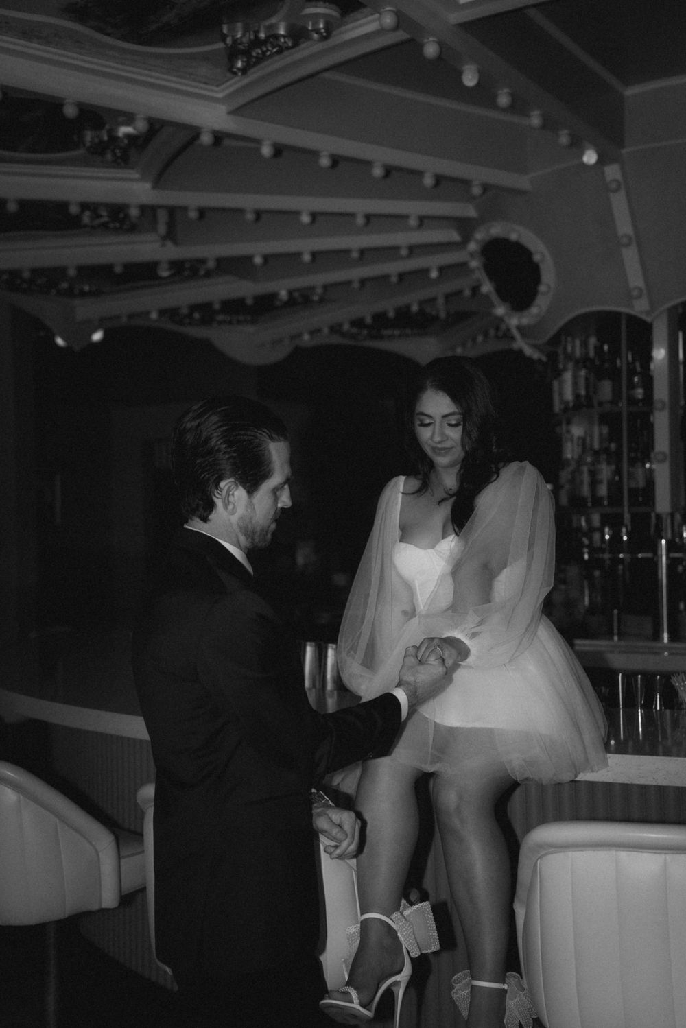 A romantic couple in formal attire sharing an intimate moment at an elegant venue with ornate architectural details.