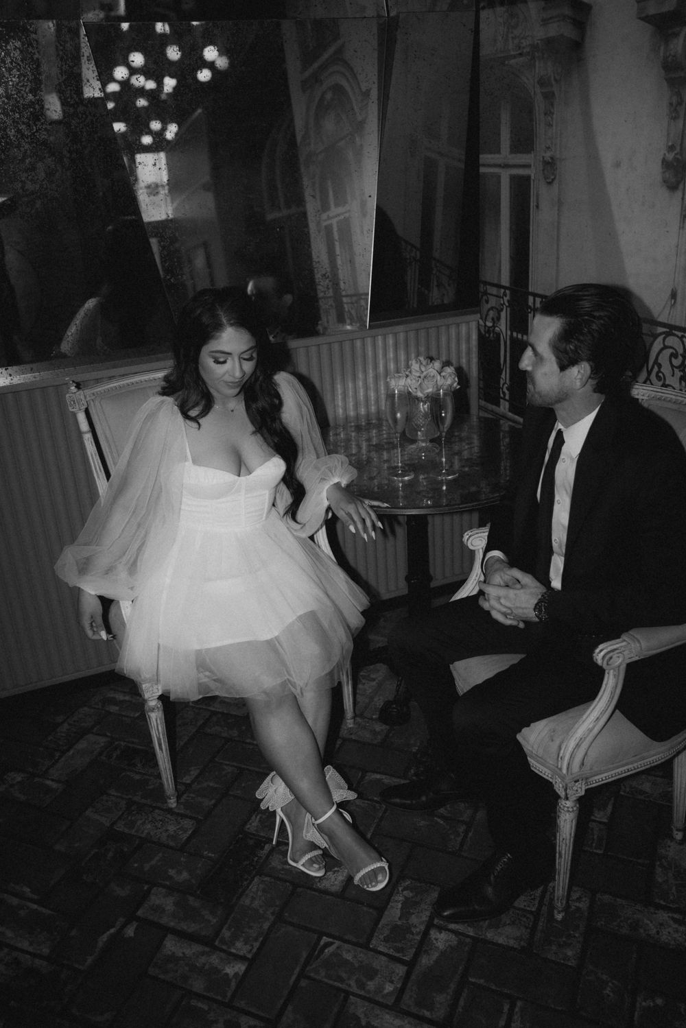 A couple shares an elegant moment in formal attire at a vintage-styled venue.