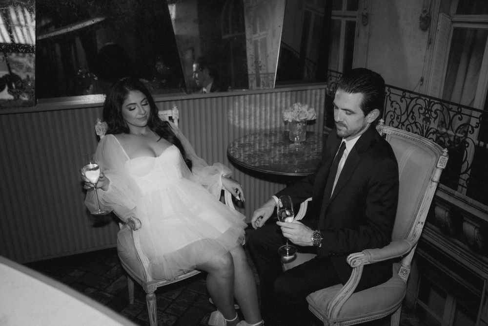Two people engaged in conversation while seated in elegant vintage chairs.