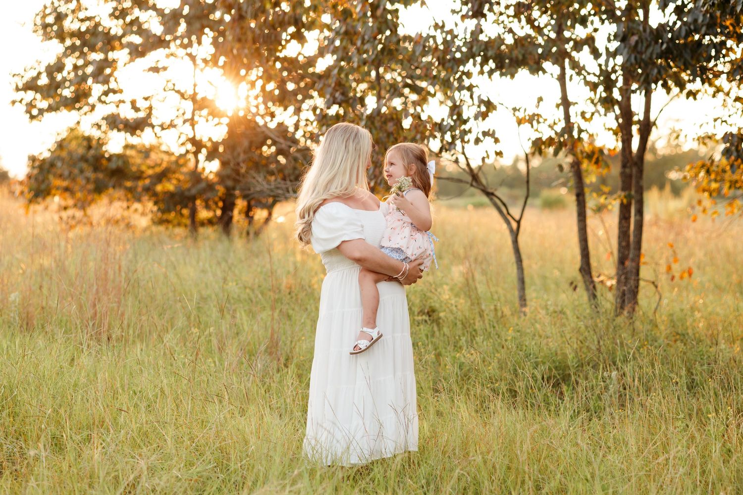 Parent lifting baby in air against blurred urban background with church dome.