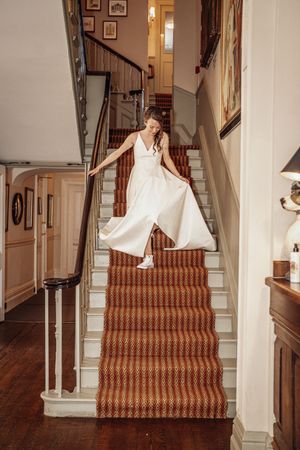 A sequence of images showing someone in a white dress sliding down a carpeted staircase with a striped runner.