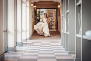 Elegant wedding photo series showing a couple in a grand hallway with arched columns and checkered floor.