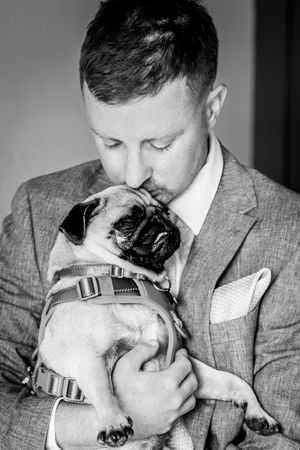 Black and white photo series showing tender moments between a person in a suit and a bulldog in close-up shots.