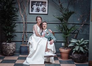 Wedding couple shares intimate moments in an indoor setting with potted plants and checkered floor.