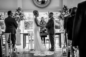 Wedding ceremony guests stand in a church while a couple exchanges vows at the altar during a traditional ceremony.
