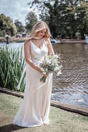 Elegant white wedding dress captured in multiple angles near a serene waterfront setting with tall reeds.