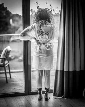 A series of black and white photos showing small feet in white socks and shoes standing by a window.