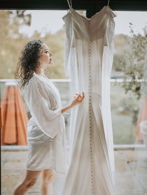 A series of photos showing a white wedding dress hanging while someone in a white shirt admires it in natural light.