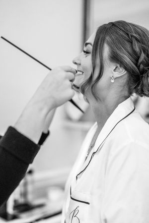 Professional makeup artist applying cosmetics to model in black and white studio photography series.