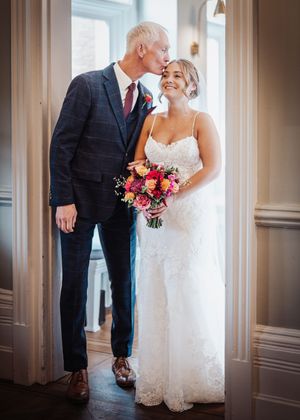 Elegant wedding couple shares intimate moments in a hallway with classic white columns and romantic lighting.