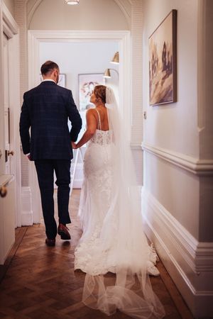 A series of photos showing a bride and groom walking down a hallway with white walls and framed artwork.