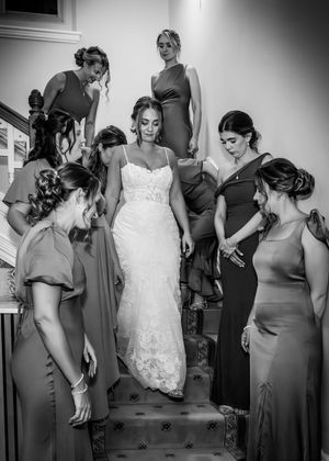 Black and white photo sequence shows bridesmaids in matching gray dresses helping adjust a bride's white lace gown.