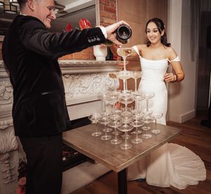 Wedding reception service staff pouring champagne into glasses at an elegant indoor venue.