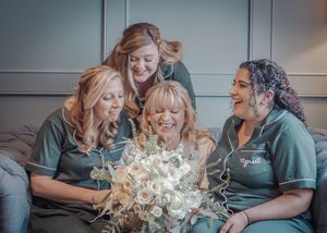 Wedding party members in matching green outfits sharing a celebratory moment with flowers.