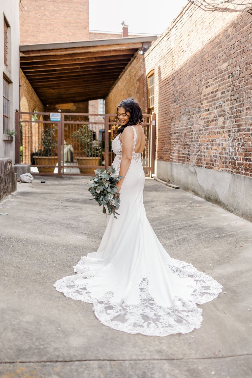 Elegant bridal portraits showcasing lace wedding dress train against industrial backdrop.