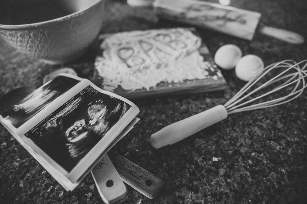 Black and white flatlay of baking ingredients and ultrasound photos on dark surface.