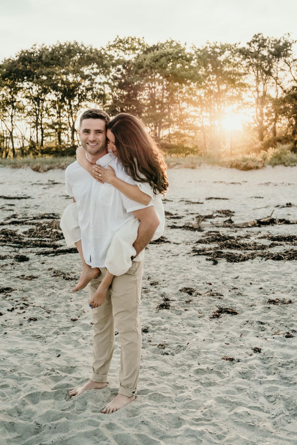 A romantic beachside moment at sunset with sand and trees in the background.