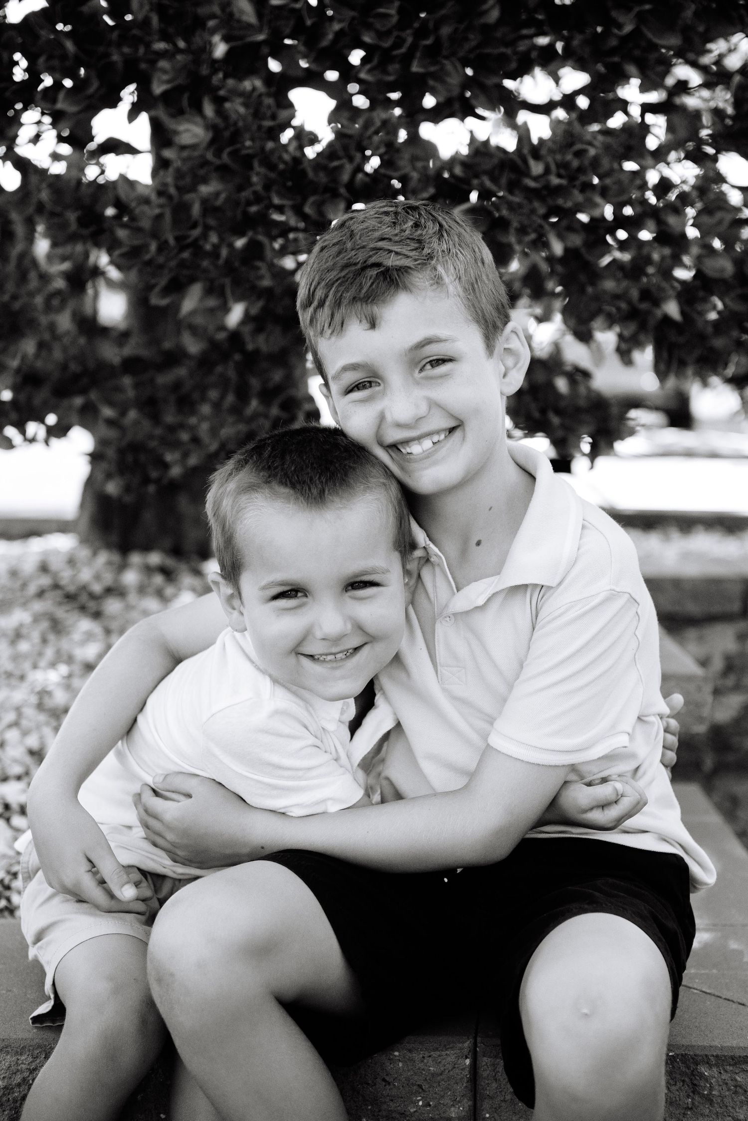 Black and white portrait of two young brothers embracing and smiling.