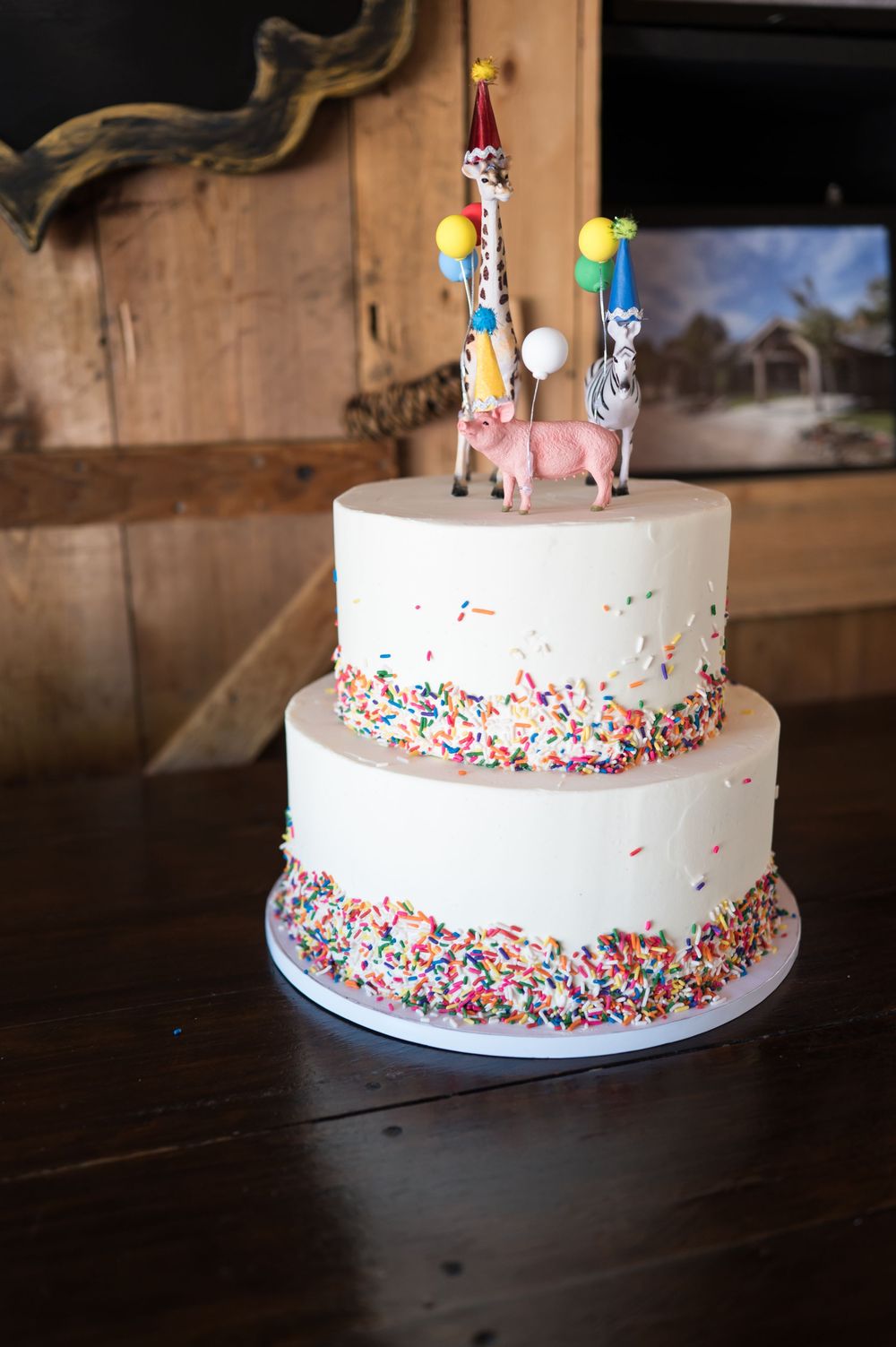 White birthday cake decorated with colorful sprinkles and party toppers on a wooden surface. Nuzzo's Farm Branford Connecticut