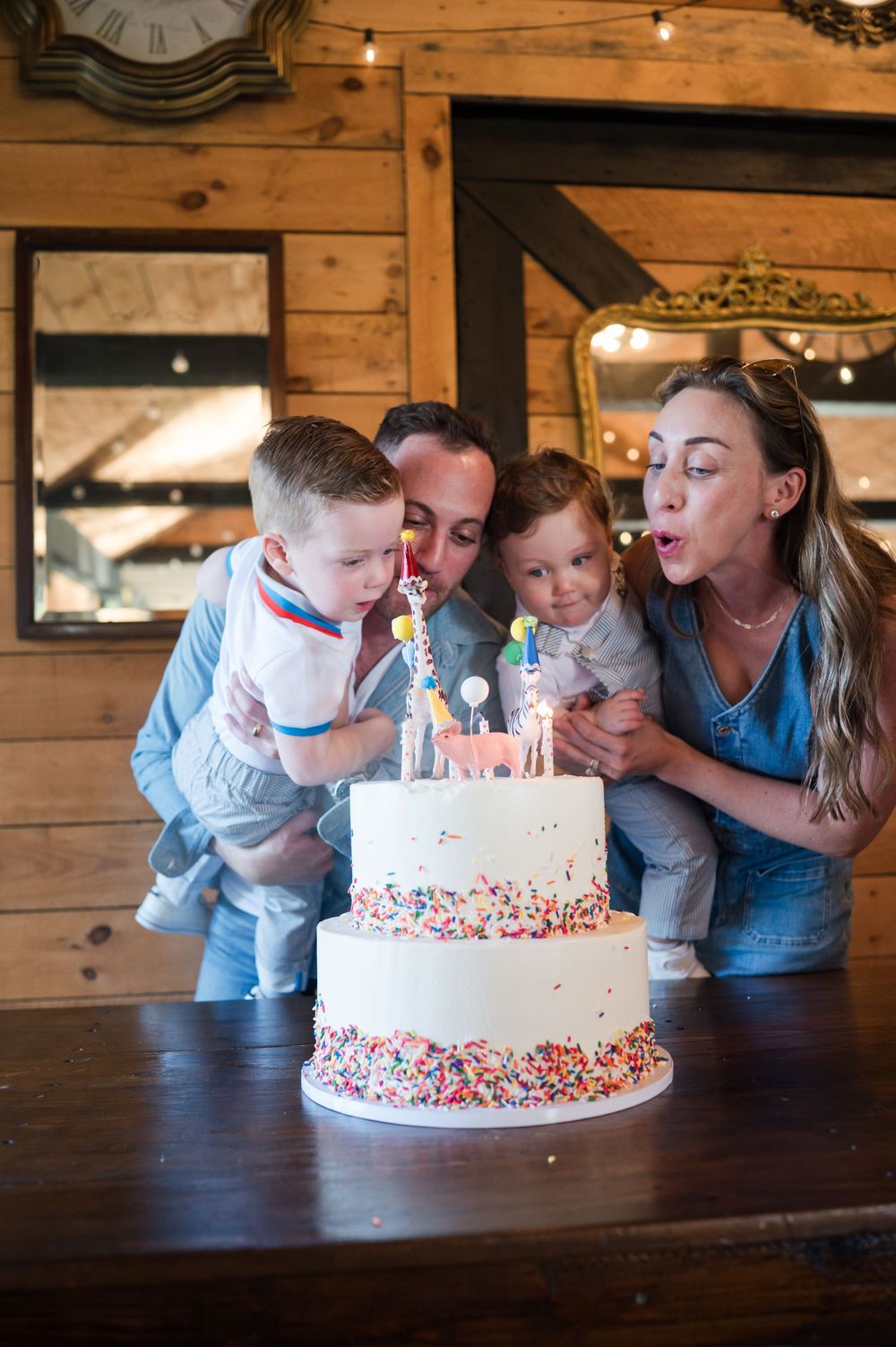 Family gathering around a white birthday cake with sprinkles on a wooden table. Nuzzo's Farm Branford Connecticut