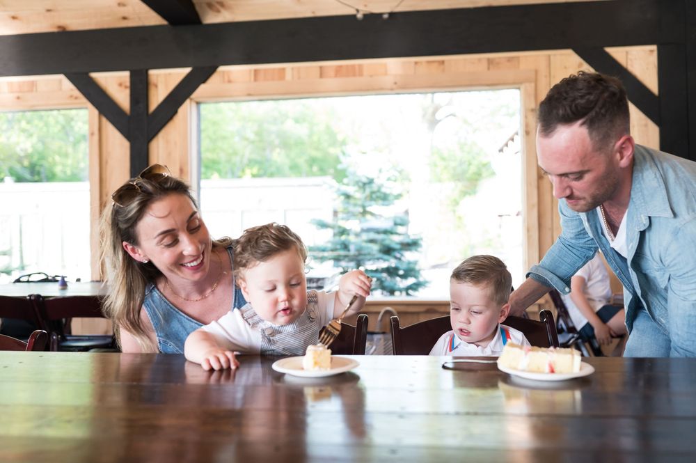 Group blowing out candles on a birthday cake in a rustic wooden room. Nuzzo's Farm Branford Connecticut