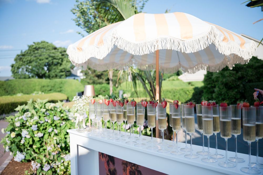 Outdoor event tent with rows of champagne glasses and decorative red garnishes.