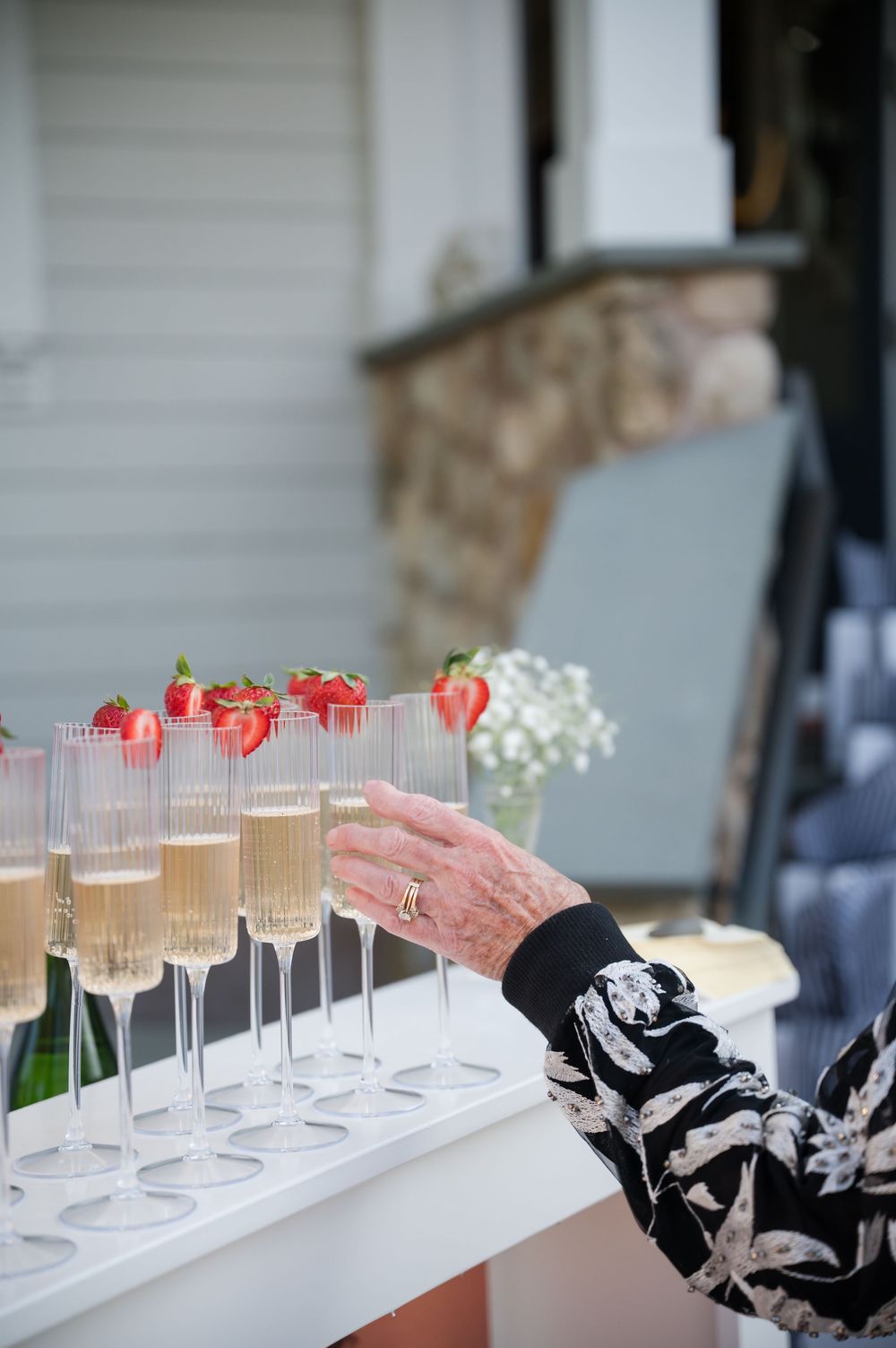 Champagne cocktails garnished with strawberries lined up on a white serving tray.