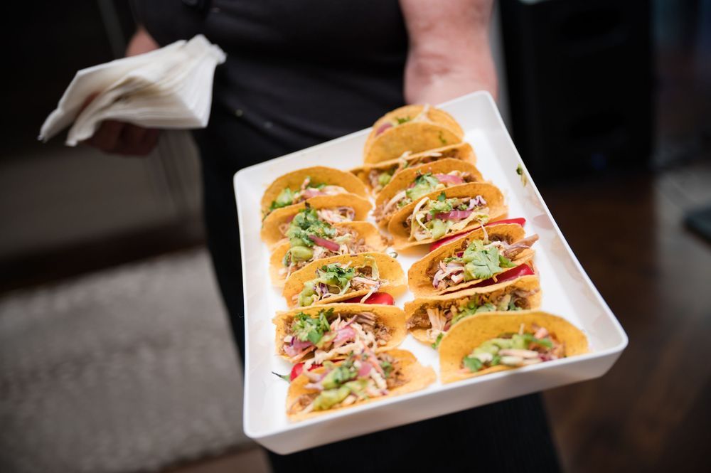 Gourmet appetizers arranged on white serving platters at a catered event.