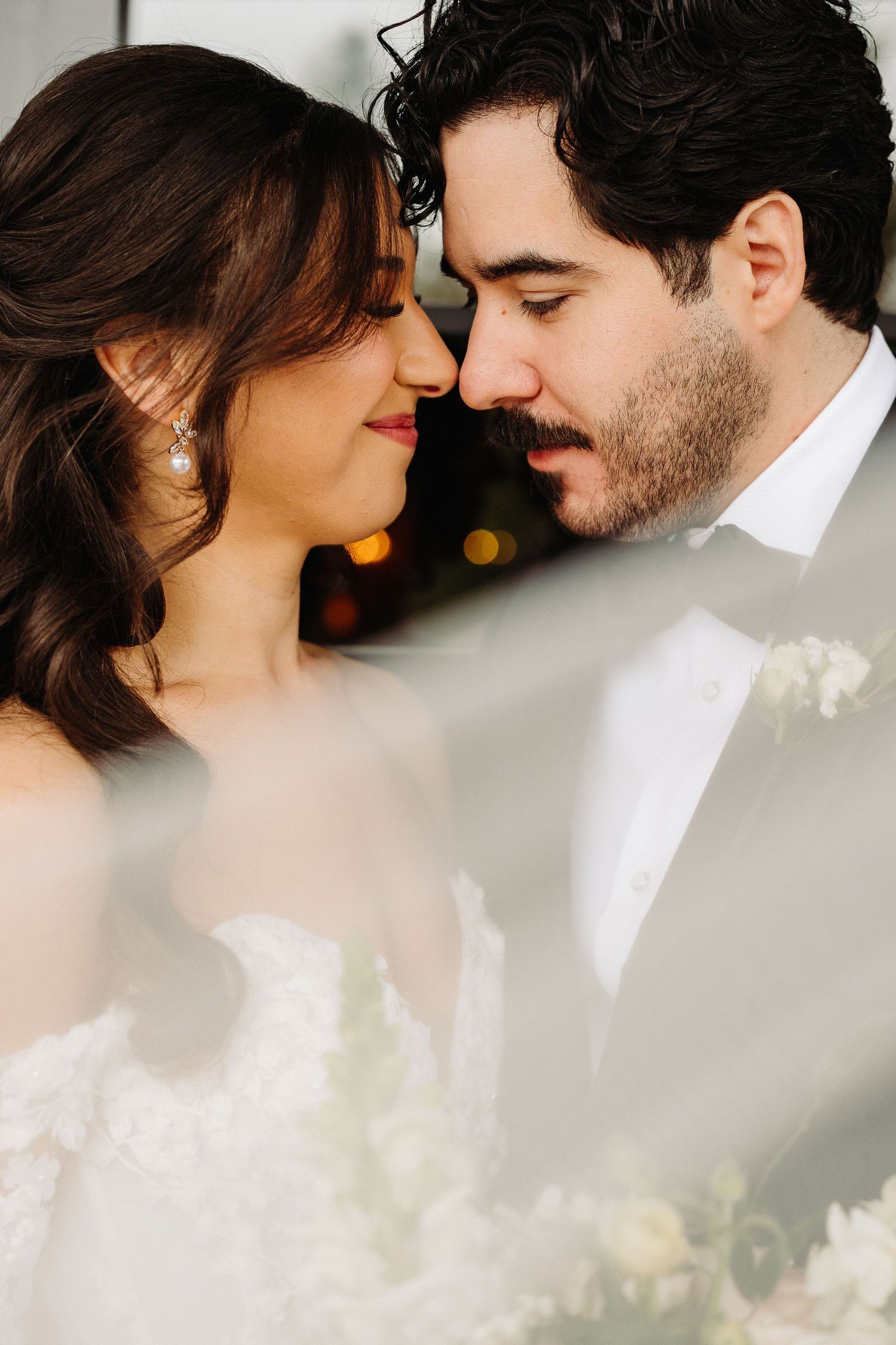 A romantic wedding portrait shows newlyweds sharing an intimate moment with their faces close together.