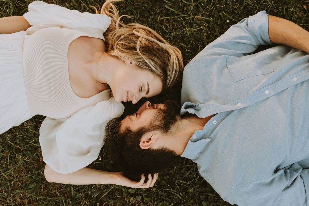 A romantic couple lying in grass during a golden hour photoshoot.