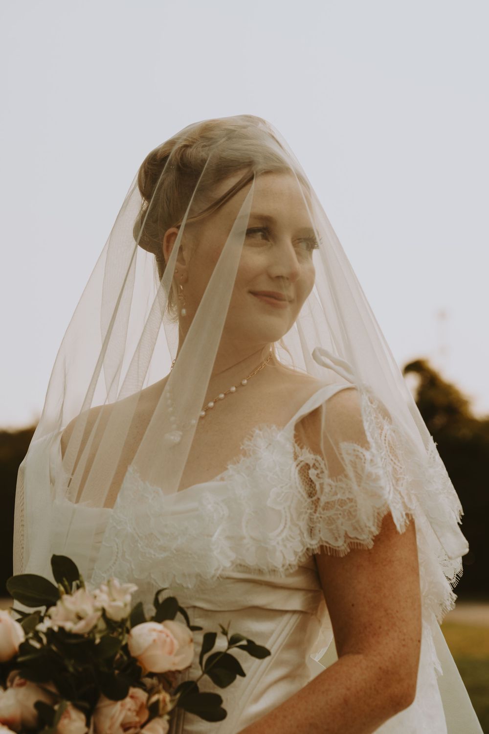 A delicate bridal veil frames a soft portrait in warm sunset light.
