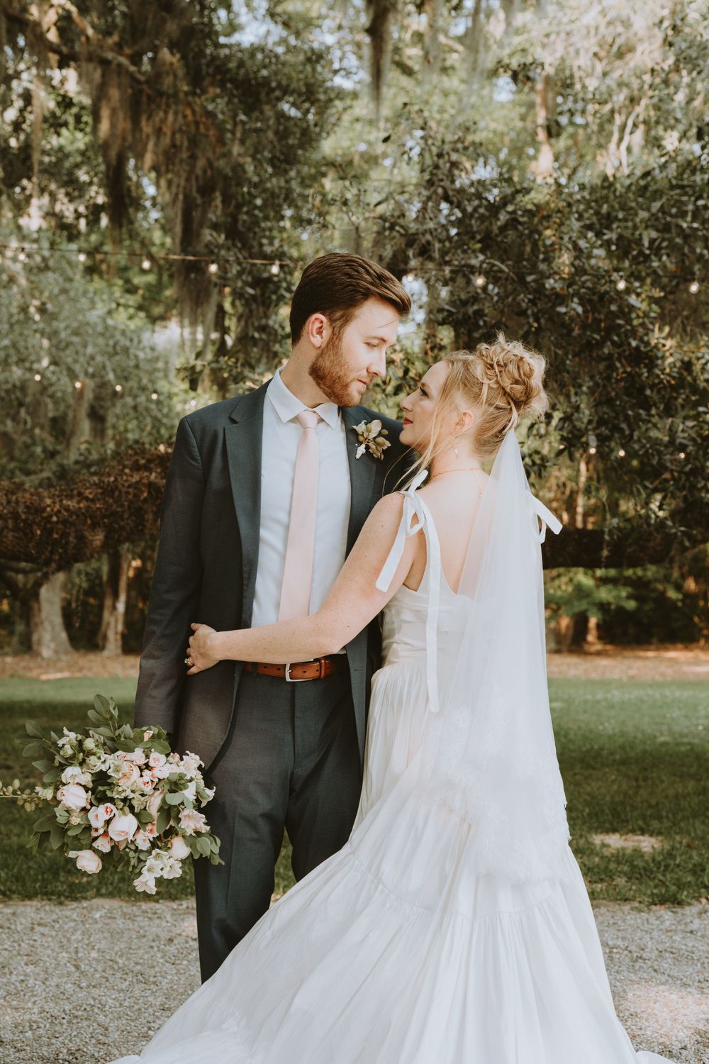 A romantic wedding moment captured in a garden setting with Spanish moss trees.