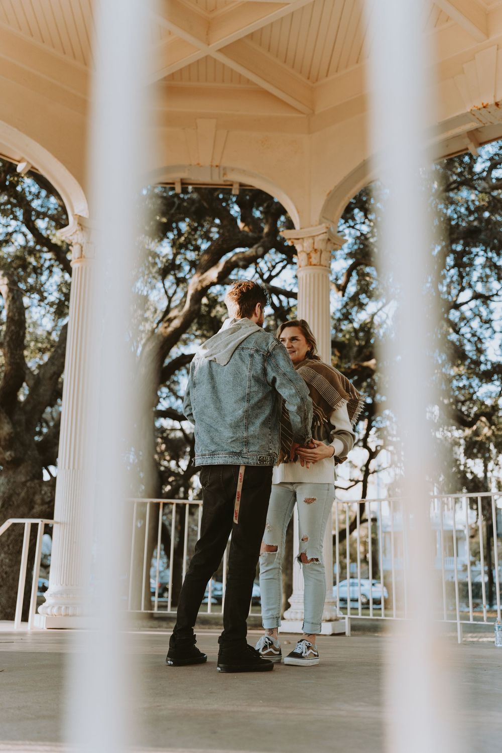 Romantic proposal scene through white columns of classic Southern-style gazebo.